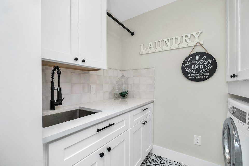 Laundry room with white cabinets, a utility sink, a light counter and a front-loading washer